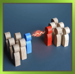 : Wooden figures with a red leader facing a group led by a blue figure, symbolising aggressive leadership dynamics.