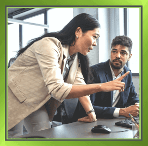 A person pointing something out to a colleague in a workplace setting, representing the Fundamental Attribution Error and the tendency to blame individual character rather than situational factors when assessing behaviour at work.